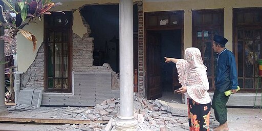 Aftermath of 2021 Malang Earthquake: two people regard a collapsed building